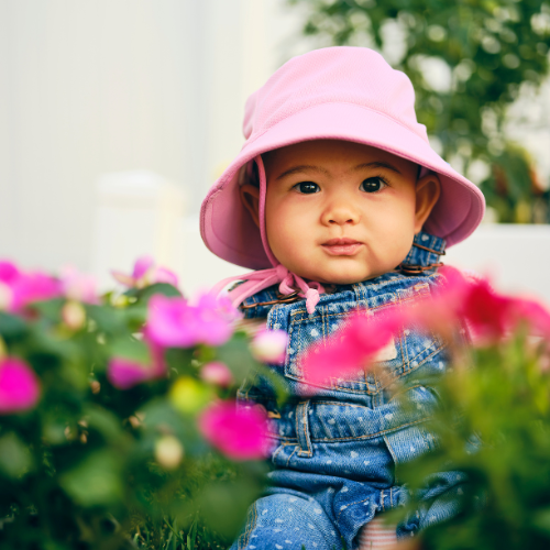 Infant with pink hat sitting outside