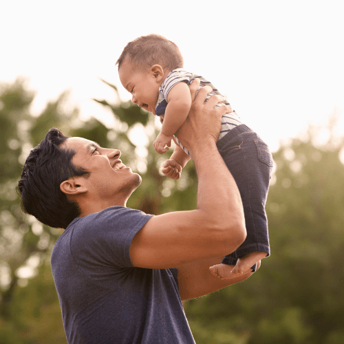 Father holding baby while standing outside
